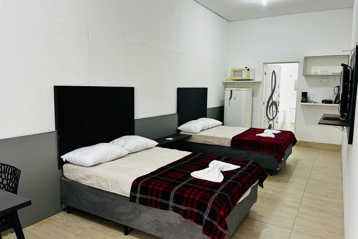 Habitación de hotel con dos camas, un escritorio, un microondas, un refrigerador y una pequeña kitchenette.