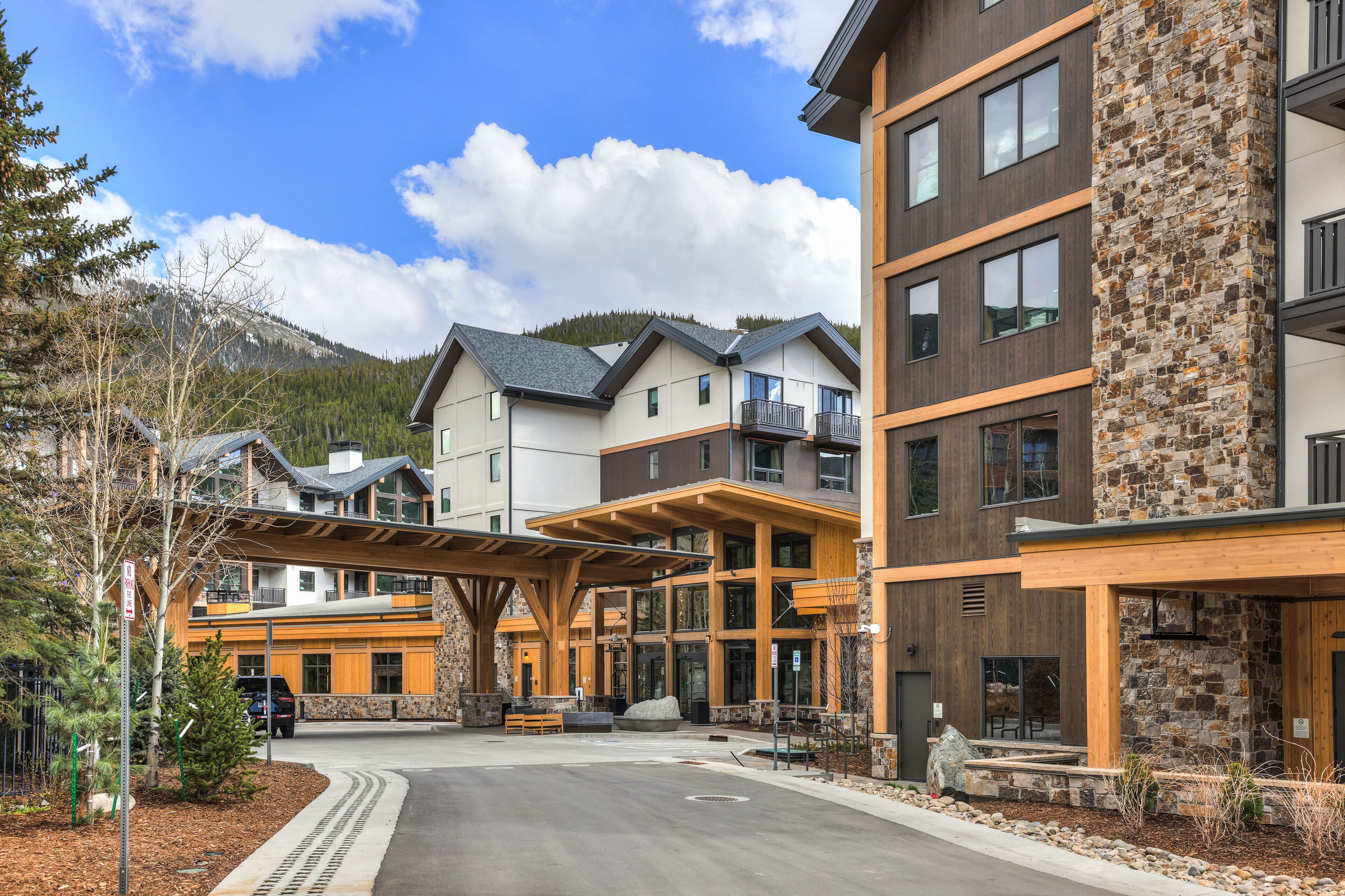 A multi-story hotel with a stone facade, wooden balconies, and a covered outdoor area with seating.