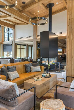 Un amplio espacio interior con un gran conjunto de asientos, una chimenea y vistas al exterior a través de amplias ventanas.