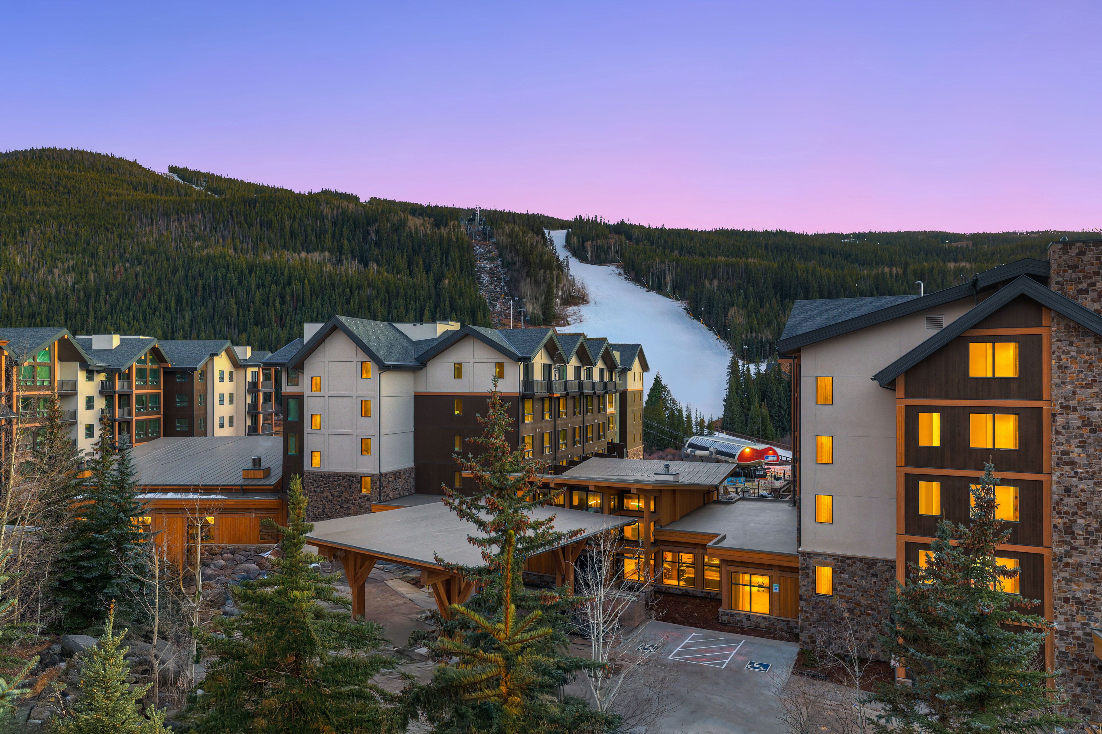 A resort with multiple buildings, a ski lift, and a mountain backdrop.