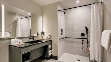 A modern bathroom with a large mirror, a sink, a shower with a glass door, and a towel rack.