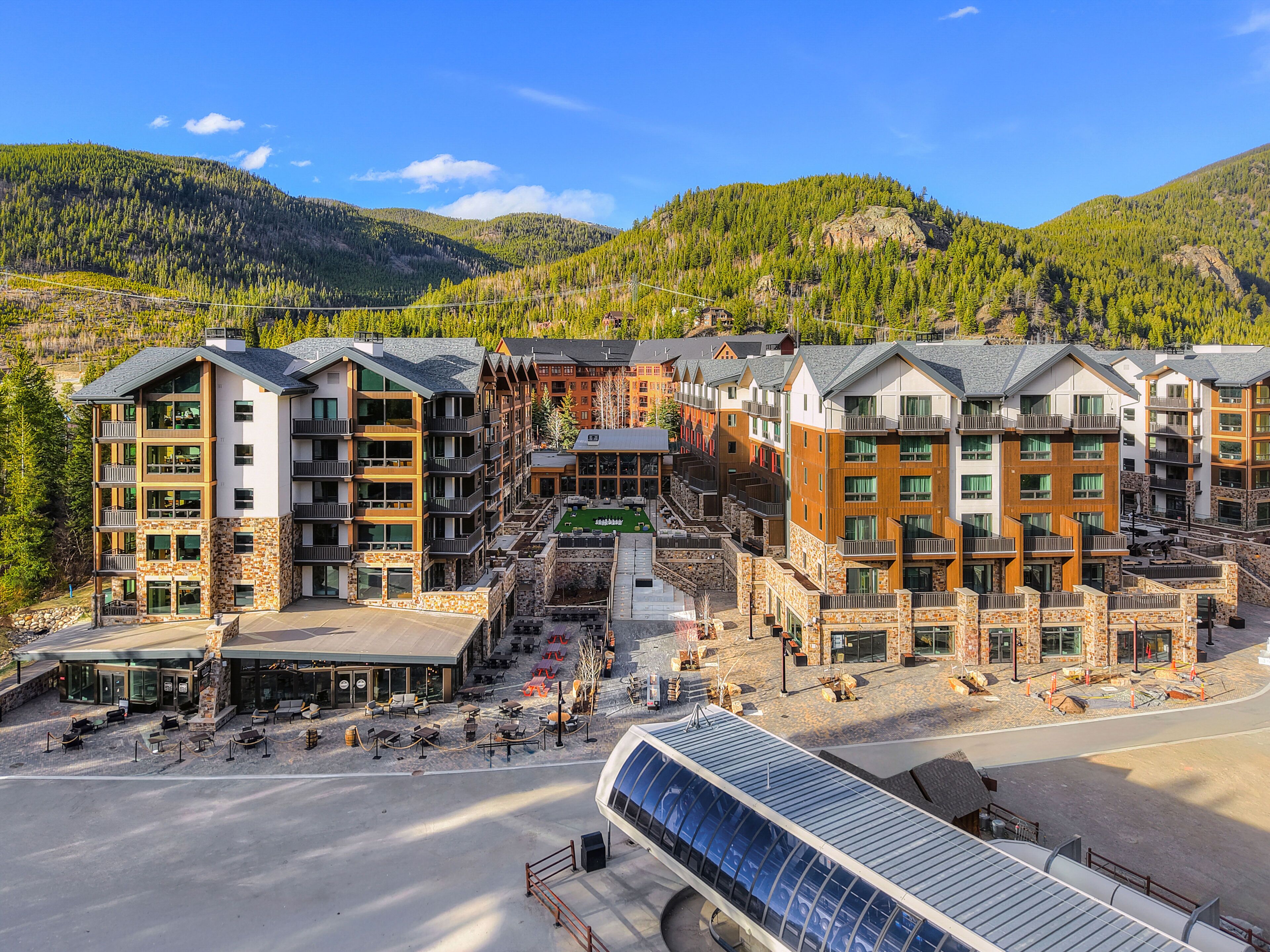 A multi-story hotel with outdoor seating and a ski lift in the foreground.