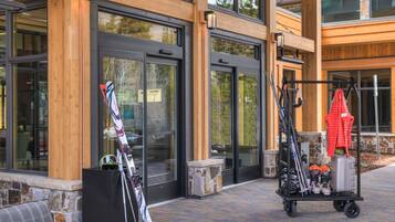 A building with large windows, a fire pit, outdoor seating, and ski equipment.