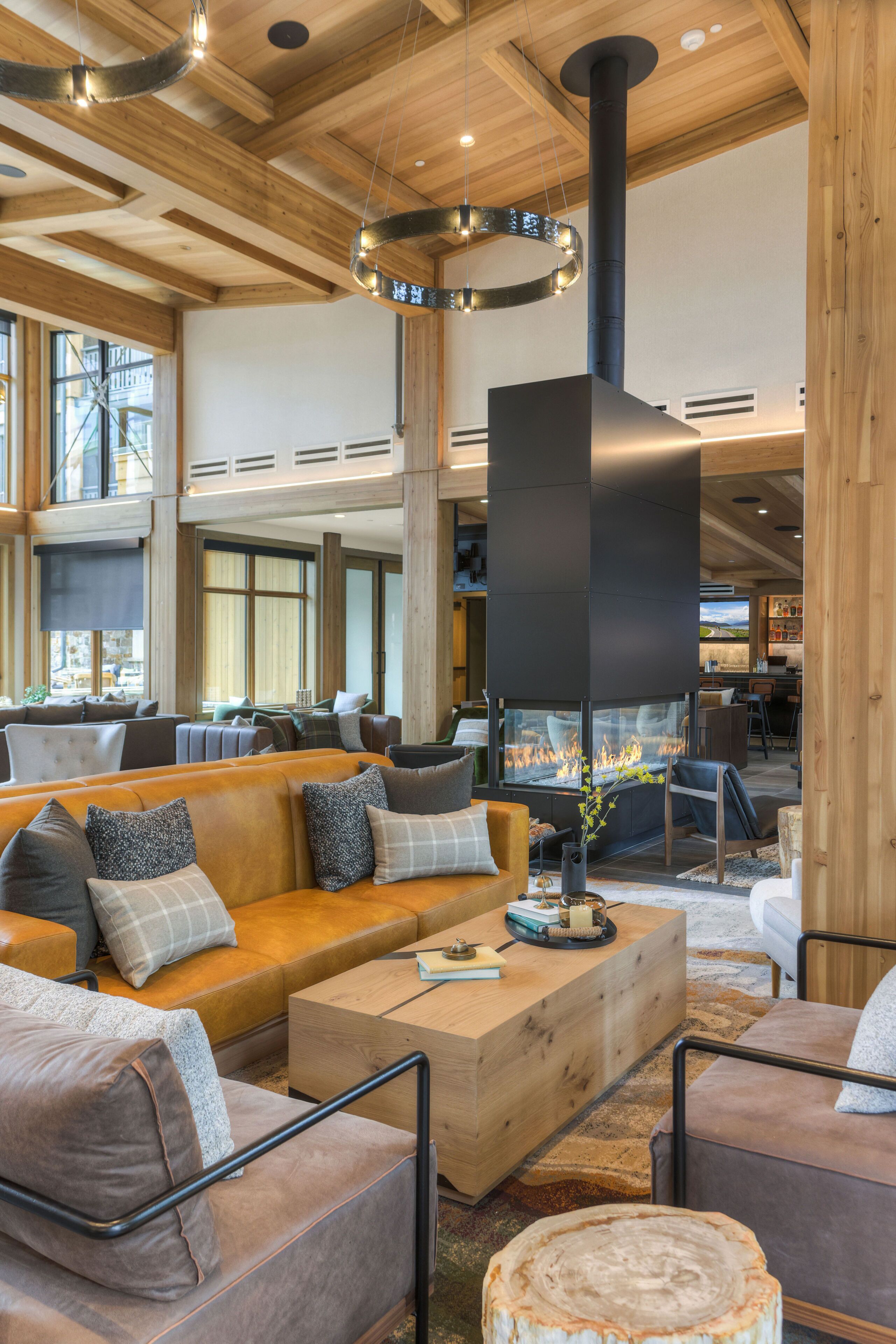 A spacious indoor area with a large seating arrangement, a fireplace, and a view of the outdoors through large windows.