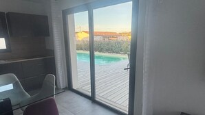 Una habitación moderna con una puerta corrediza de vidrio que da a una terraza de madera con piscina.