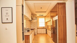 A modern kitchen with wooden cabinets, a marble backsplash, and a built-in oven. - Midak Mews 2 Oceanview Luxury Apartments (Lekki)