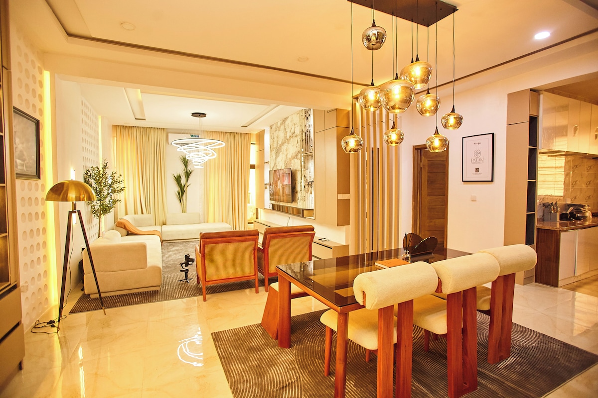 Un comedor moderno con una mesa de madera, sillas y lámparas colgantes.