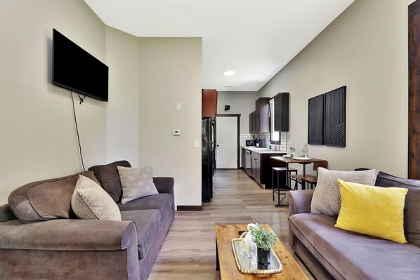 A modern living room with a sofa, coffee table, and a flat-screen TV mounted on the wall.