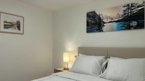 Une chambre d’hôtel avec un lit, une table de chevet avec une lampe et deux tableaux encadrés au mur.