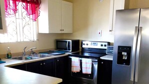 A compact kitchen with a sink, microwave, stove, and refrigerator.