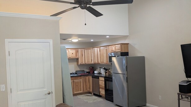 A modern kitchen with wooden cabinets, stainless steel appliances, and a ceiling fan. - Barndo in the Rocky Mt Woods (Rocky Mount)
