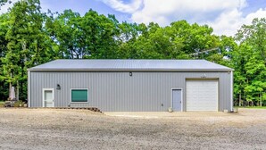 A single-story metal building with a garage door, a small window, and a door. - Barndo in the Rocky Mt Woods (Rocky Mount)