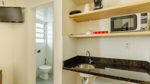 A compact kitchen with a microwave, a sink, and a small countertop. - Studio With Prime Location in POA - Els0606 (Porto Alegre)