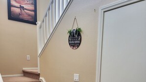 Un escalier avec un porte-chaussures et un paillasson sur lequel est écrit : « Veuillez enlever vos chaussures ».