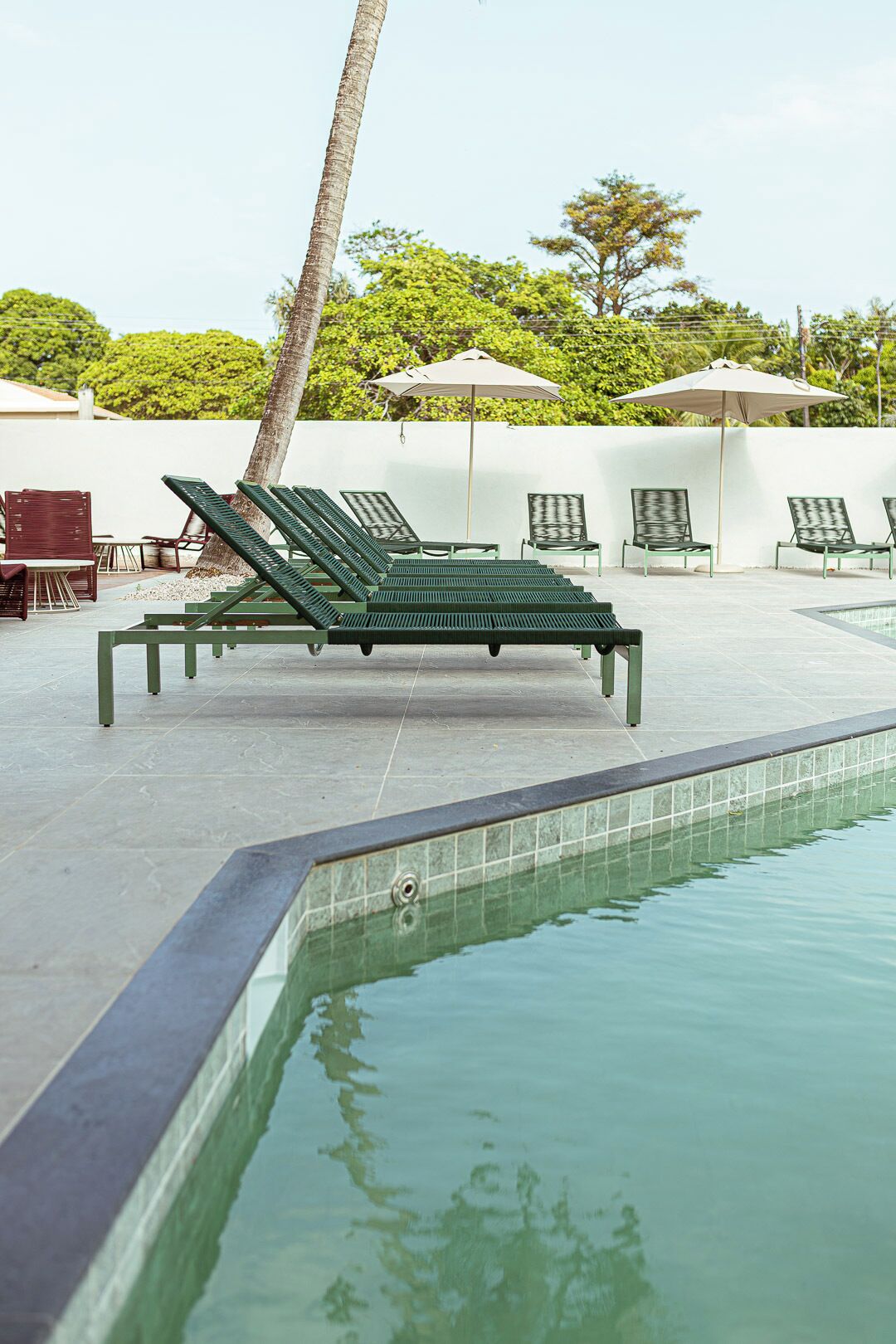 A pool area with lounge chairs and umbrellas.