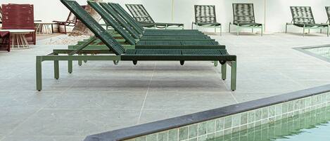 A pool area with lounge chairs and umbrellas.