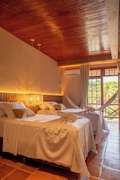 Un dormitorio con dos camas, techo de madera, unidad de aire acondicionado y vistas a la vegetación por la ventana.