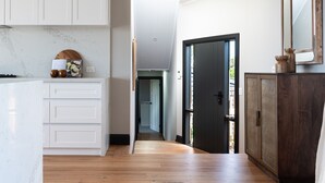 Una cocina moderna con armarios blancos, encimera de madera y vistas al comedor.