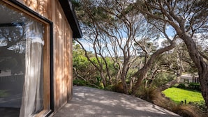 Una casa moderna con un amplio ventanal y un camino de hormigón que conduce a una zona verde.