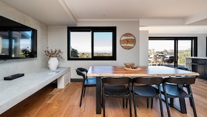 Un comedor moderno con una mesa de madera, sillas negras y vistas amplias a través de grandes ventanales.