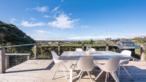 An outdoor dining area with a table and chairs, a grill, and a view of the landscape. - Capeviews on Higgins with separate Studio (Rye)