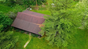Luchtbeeld van een huis met een schuin dak, omgeven door weelderige begroeiing.