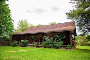 A rustic wooden cabin with a porch, two rocking chairs, and a 'Welcome' sign.