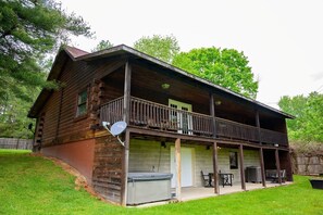 A log cabin with a covered porch, a satellite dish, and a small outdoor seating area.