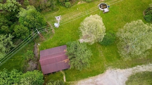 An aerial view of a property with a large metal shed, a circular water tank, and a grassy area with trees.