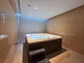 A modern bathroom with a freestanding hot tub, a bench, and a tiled floor.