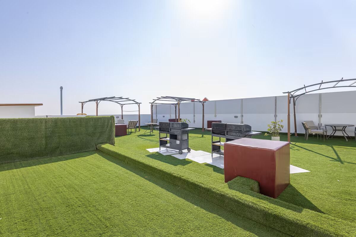 A rooftop terrace with artificial grass, outdoor furniture, and a barbecue area.
