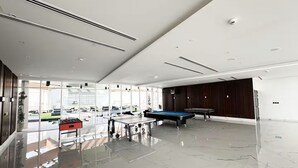Amplo espaço interno com mesa de bilhar, mesa de pebolim e mesa de sinuca.