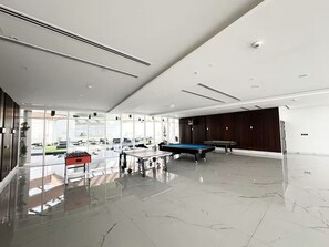 A spacious indoor area with a pool table, foosball table, and a billiards table.
