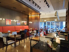 A modern restaurant interior with booths, tables, and a bar area.