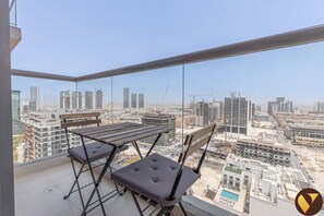 A balcony with a view of a cityscape, featuring high-rise buildings and construction cranes.