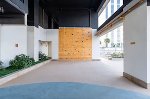 A modern interior with a climbing wall, a blue carpeted area, and a white wall with a small plant.