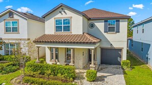A two-story house with a tiled roof, a garage, and a well-maintained garden.