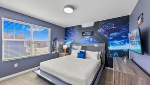 Une chambre à coucher avec un grand lit, une table de chevet, une fresque murale et une fenêtre avec des stores.