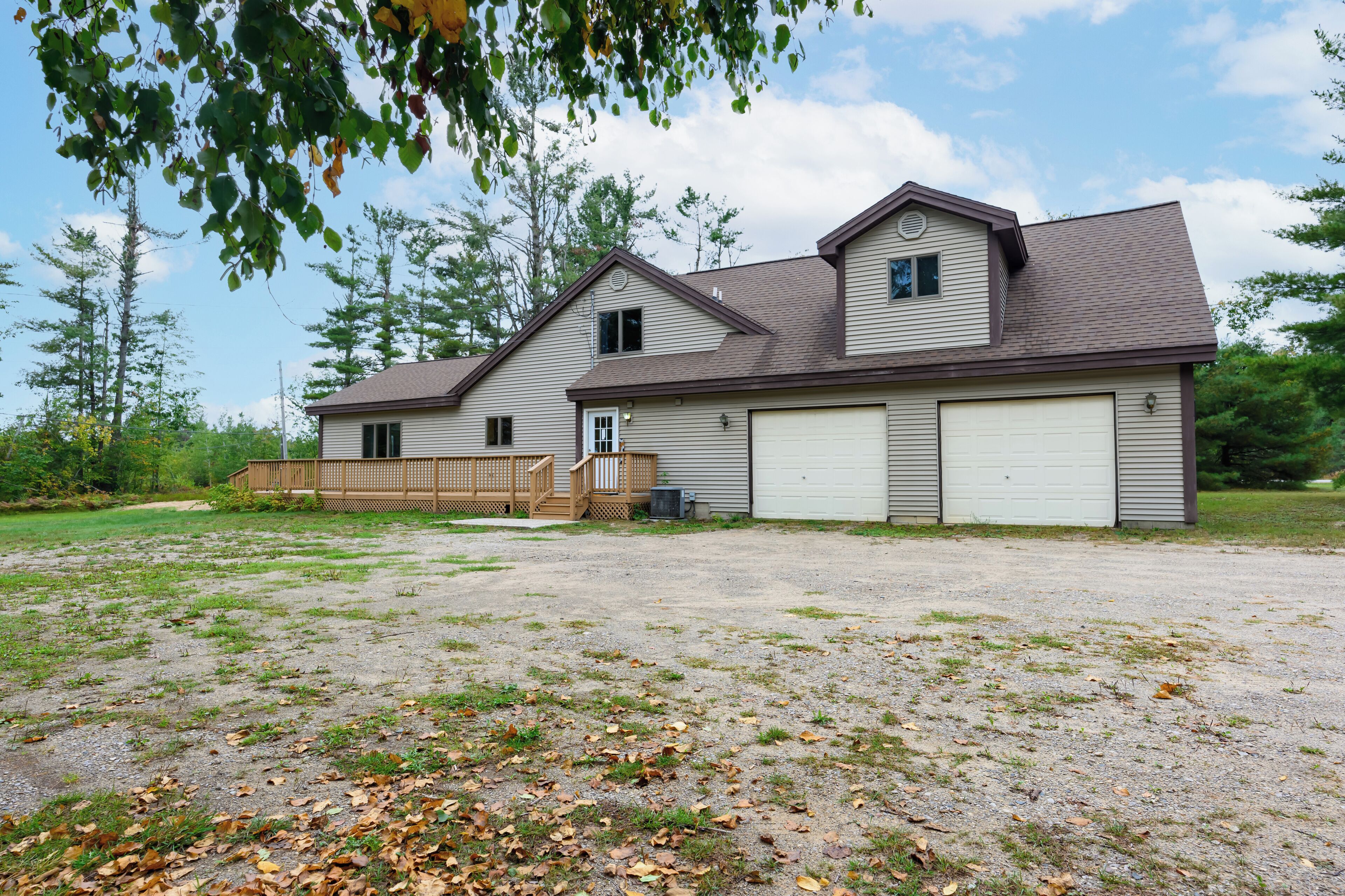 A two-story house with a garage, a covered porch, and a gravel driveway.