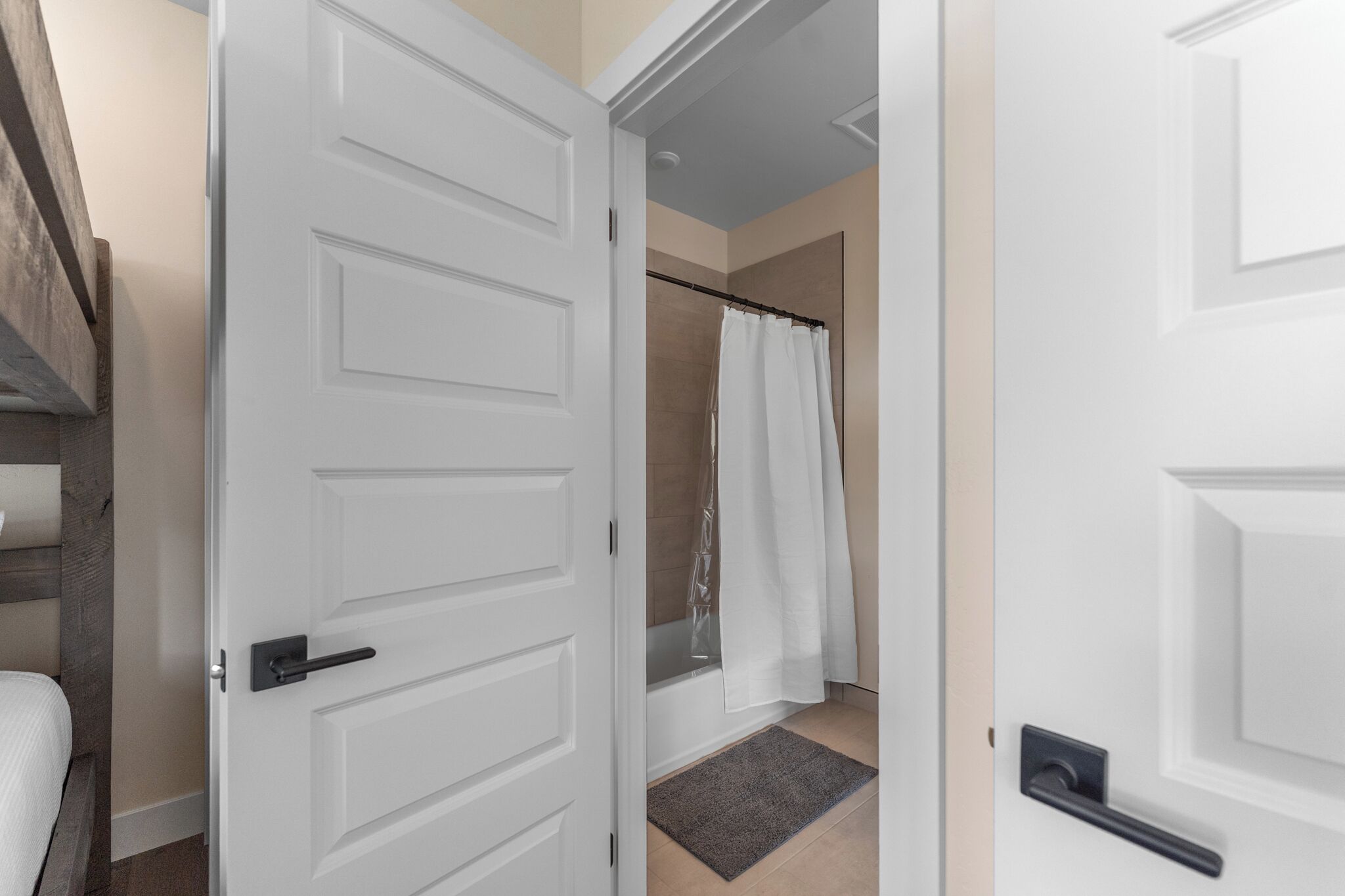 Une salle de bain avec une porte blanche, un rideau de douche et une baignoire.
