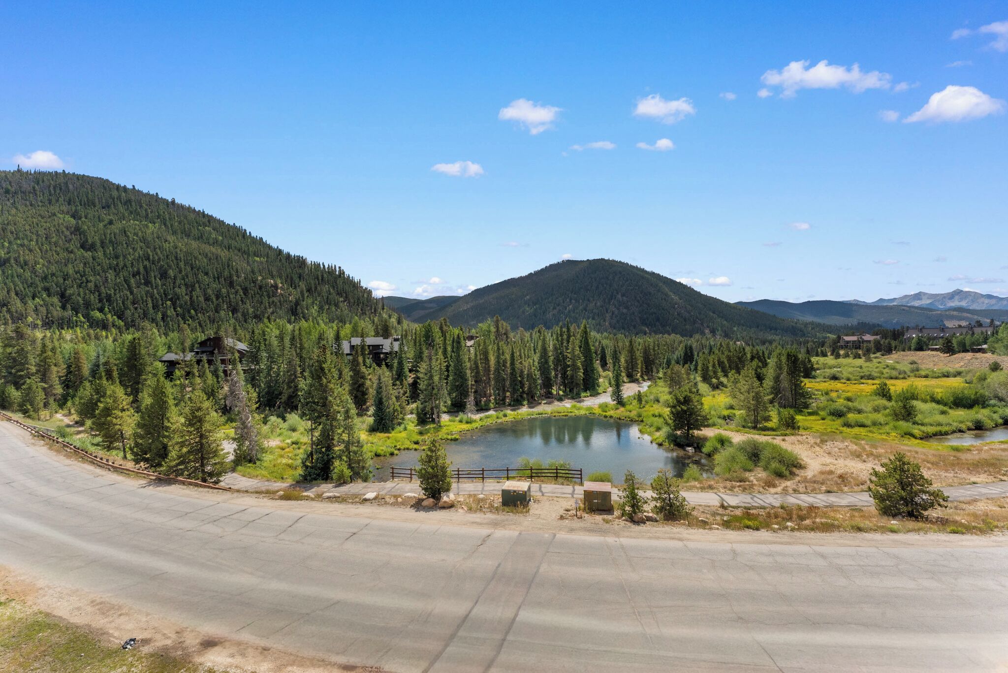 A scenic landscape with a lake, forested hills, and a road.