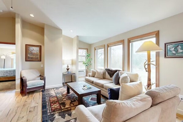 A living room with a sofa, armchair, coffee table, and a rug.