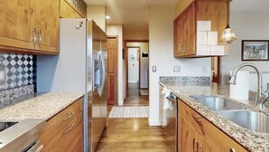A kitchen with wooden cabinets, granite countertops, stainless steel appliances, and a pendant light. - Peaceful Mountain View Home – Dog Friendly (Kalispell)