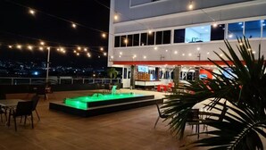 A rooftop terrace with a pool, outdoor seating, and a bar area. - Mirago Hotel (Yumbo)