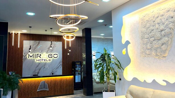 A hotel reception area with a modern design, including a marble reception desk, a sofa, and a unique wall art piece. - Mirago Hotel (Yumbo)