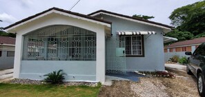 Uma casa térrea com fachada branca e telhado azul.