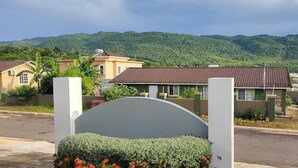 A residential area with houses, a road, and a mountainous backdrop.