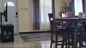 A spacious room with a high ceiling, a dining area with a table and chairs, a ceiling fan, and a sign that reads "HOME".