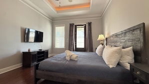 Un dormitorio ordenado con cama, televisor, mesita de noche y lámpara.