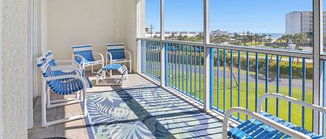 A balcony with blue-striped chairs and a patterned floor mat.